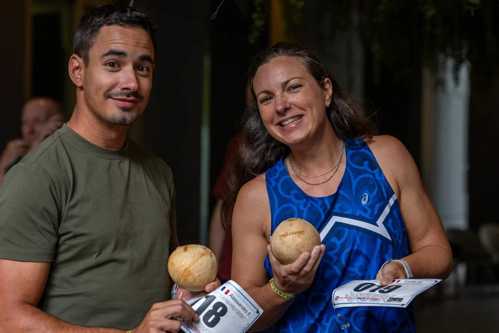 Two runners holding their race bibs and Rex Cargo coconuts